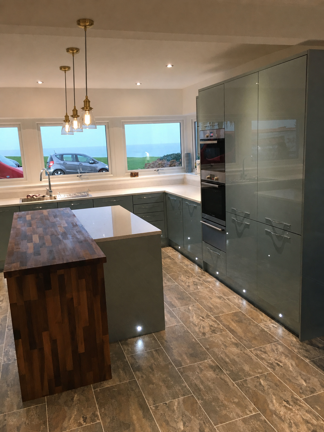 Completed gloss kitchen with island and feature pendant lighting